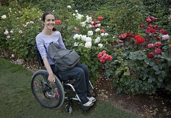 Image of a young woman in a wheelchair in front of a flowers